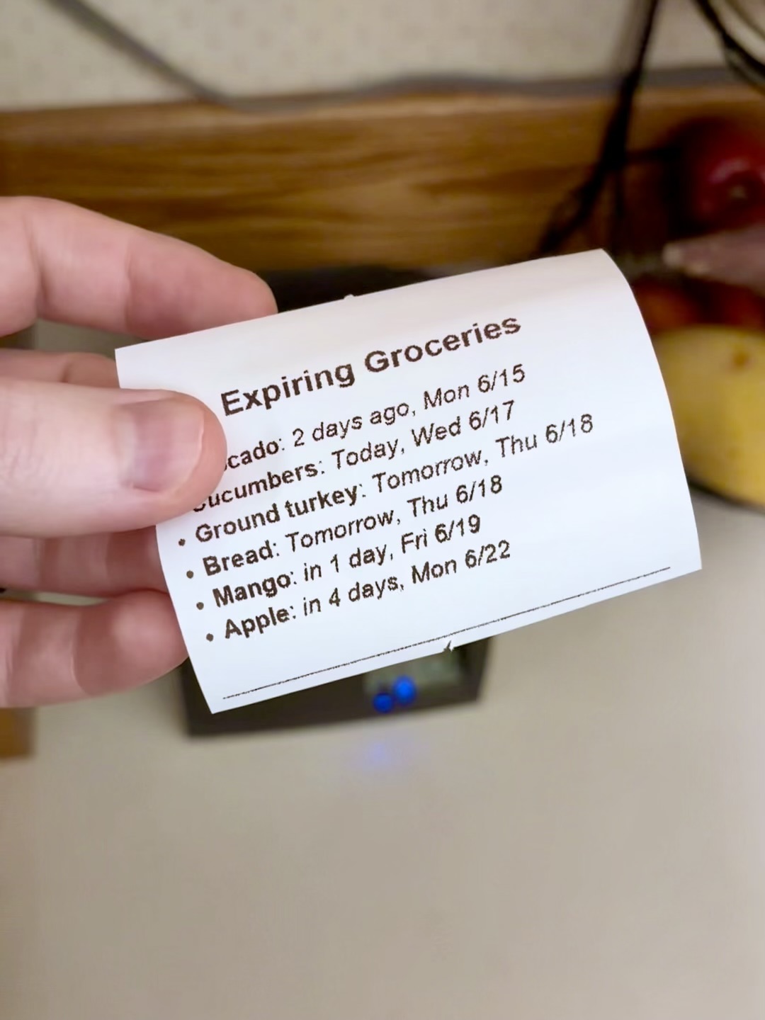 A hand holding a printed receipt titled Expiring Groceries with items and dates.